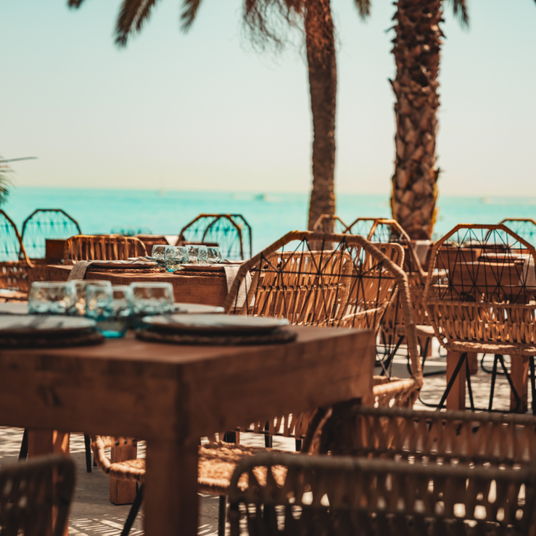 Terraza frente al mar · Kanaloa Marbella Terraza de Kanaloa Marbella con mesas, palmeras y vistas al mar Mediterráneo